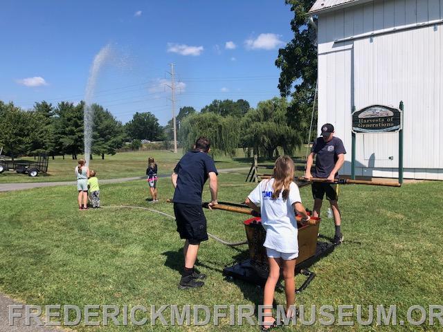 Kids love pumping and spraying water using the small historic hand pump owned by museum member Doug Riddle 